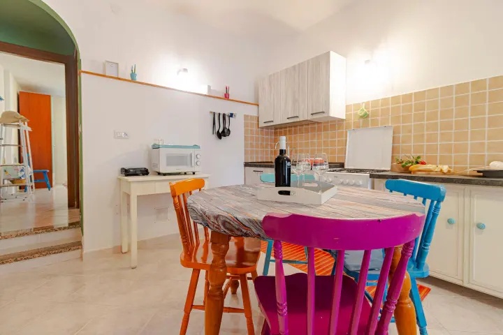 Tavolo da pranzo con sedie colorate accanto alla cucina.