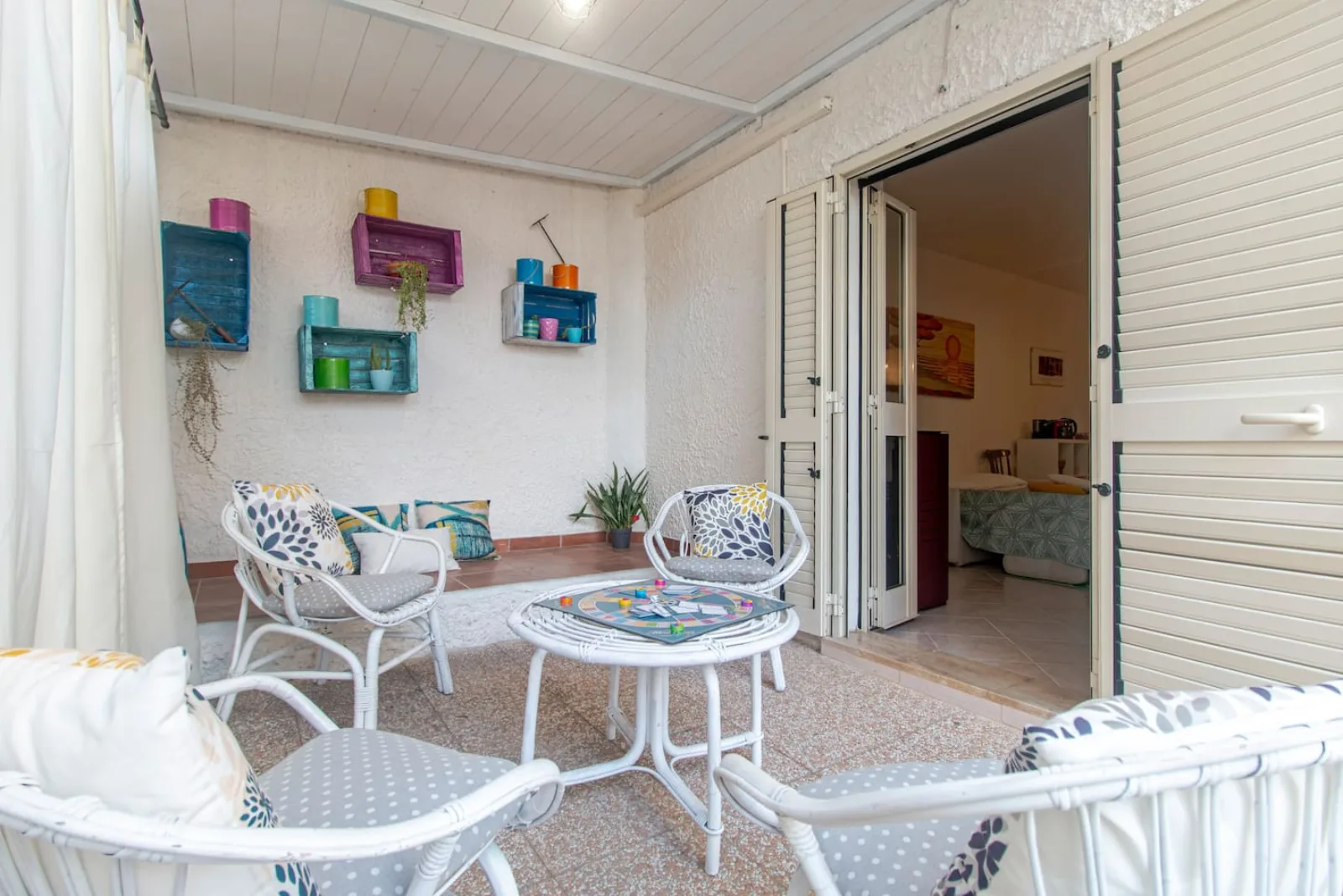 Veranda coperta con sedute bianche e accesso diretto all’appartamento.